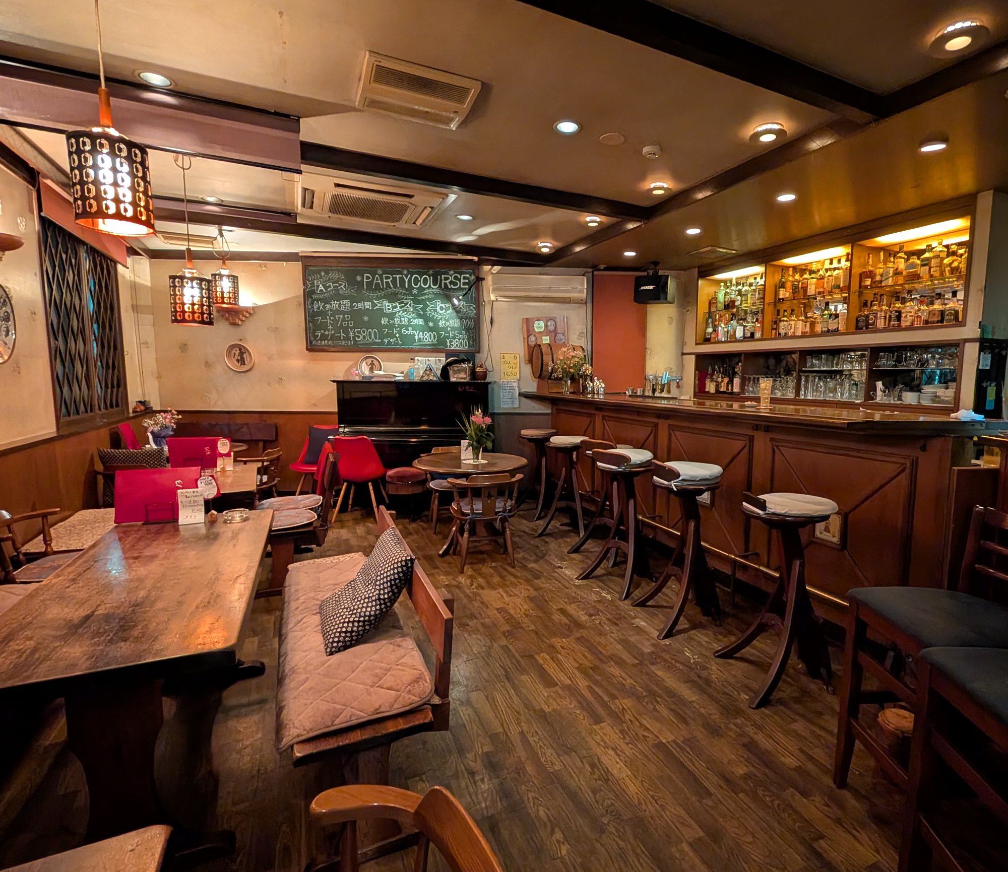 El Galán の店内。木のカウンターとテーブル席、奥にはピアノとパーティーコースの黒板