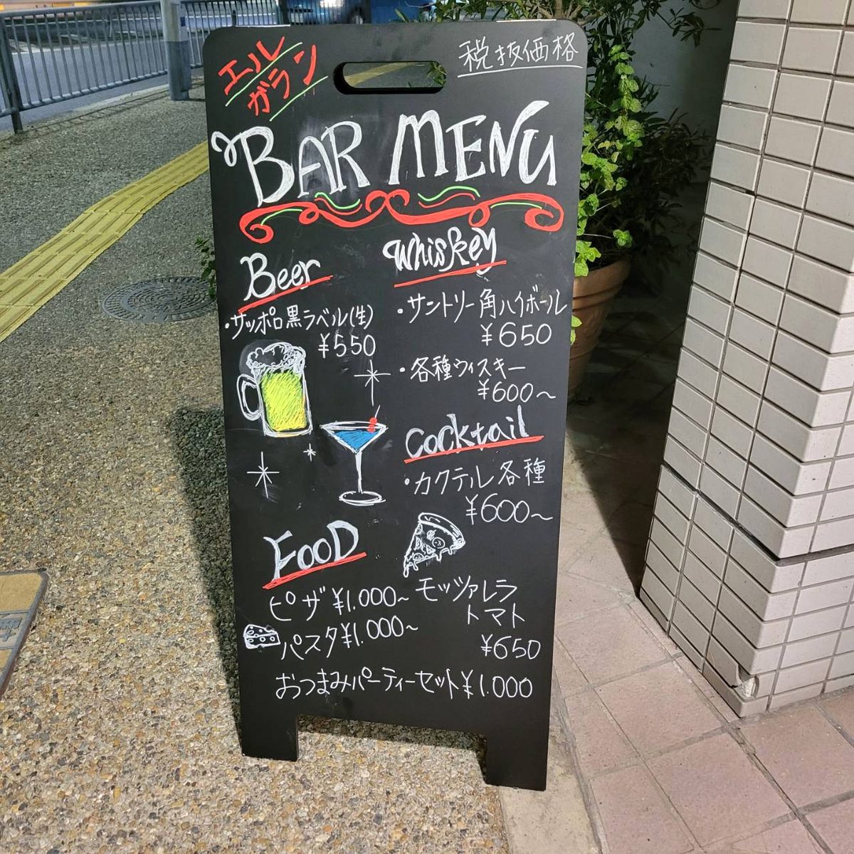 店頭の黒板に手書きされたBAR MENU。ビール、ウイスキー、カクテル、フードの価格が並ぶ